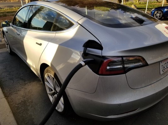 auto elektromobil Tesla Model 3 u nabíjecí stanice Tesla Supercharger