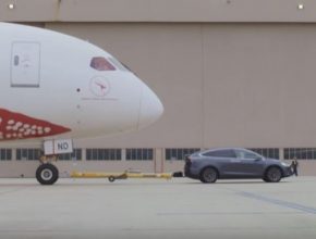 auto elektromobil Tesla Model X táhne po letištní pojezdové dráze letadlo Boeing 787-9 Dreamliner