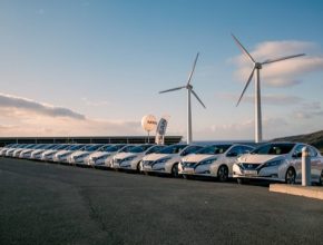 elektromobily Nissan Leaf s větrnou elektrárnou v pozadí čekají na své nové norské majitele