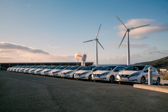 elektromobily Nissan Leaf s větrnou elektrárnou v pozadí čekají na své nové norské majitele