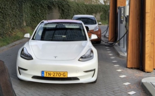 auto elektromobil Tesla Model se na bíjí na nabíjecí stanici Fastned konektorem CCS
