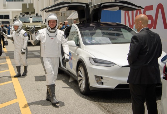 Astronauti Bob Behnken a Doug Hurley právě vystoupili z elektromobilu Tesla Model X a vydávají se na cestu k ISS.